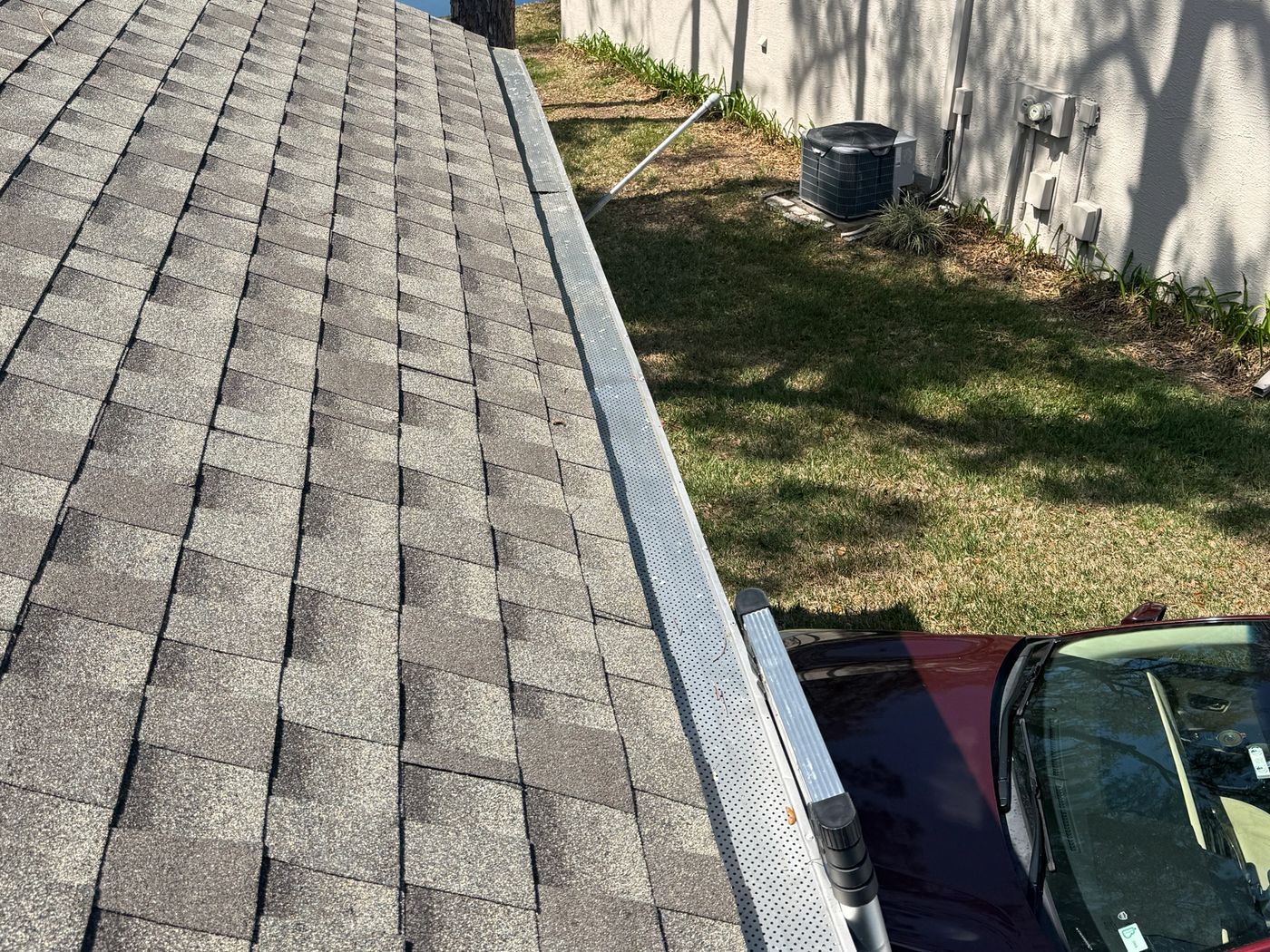 Clear, fully cleaned gutter running along a shingle roofline
