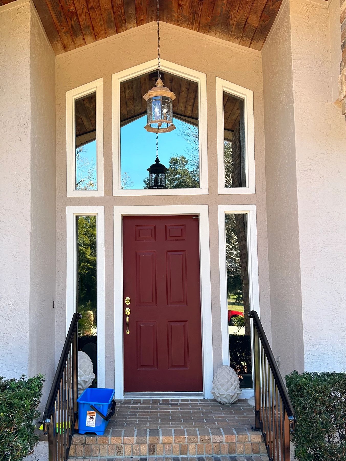 Cleaned entryway glass around a red front door with tall sidelights and transom windows